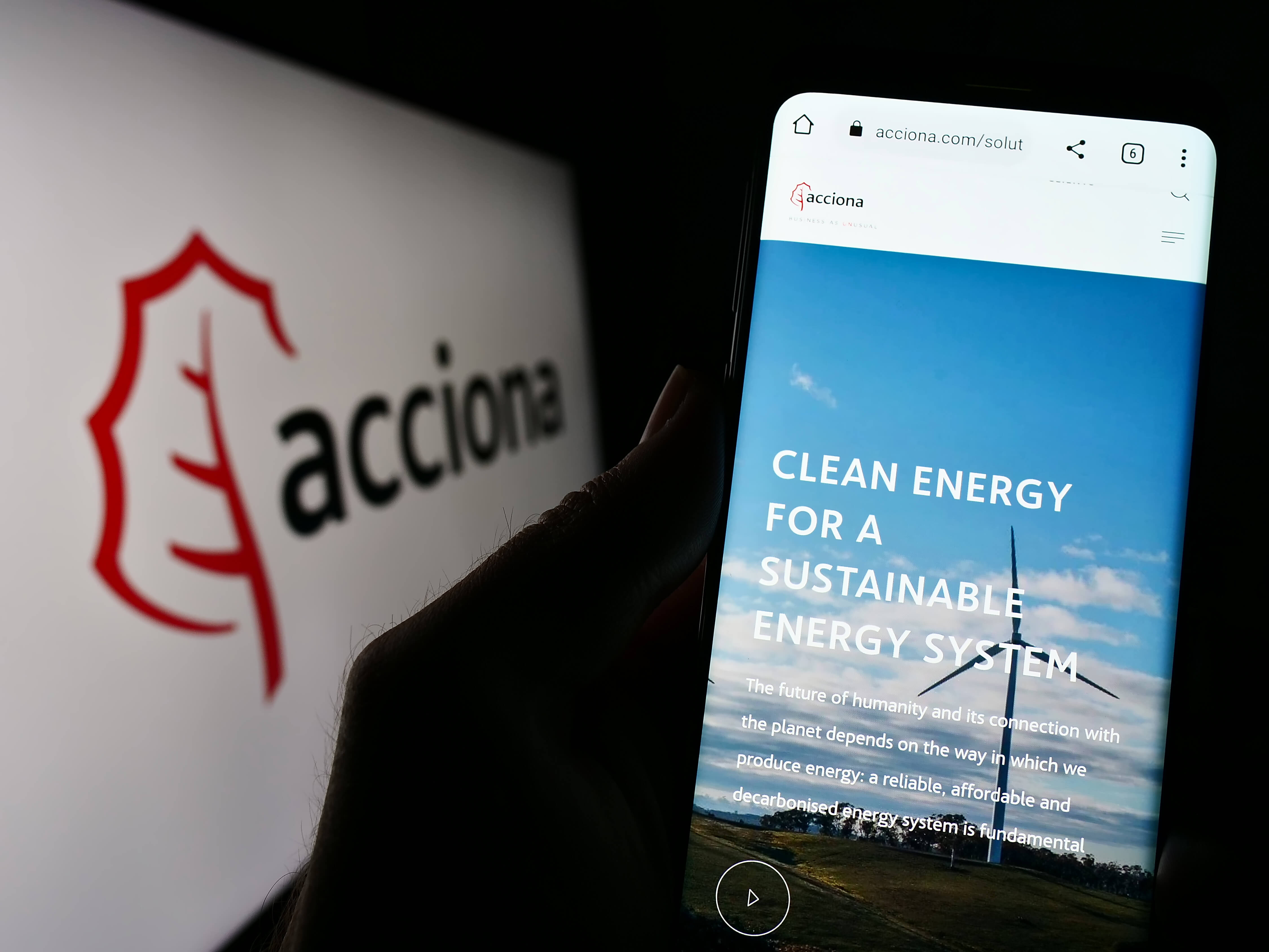 Stuttgart, Germany – 04-16-2023: Person holding cellphone with webpage of Spanish infrastructure company Acciona SA on screen in front of logo. Focus on center of phone display.