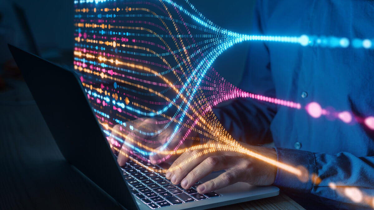 Programmer typing on laptop with colorful data flow visualization, concept of artificial intelligence, big data analysis, machine learning, and digital technology innovation
