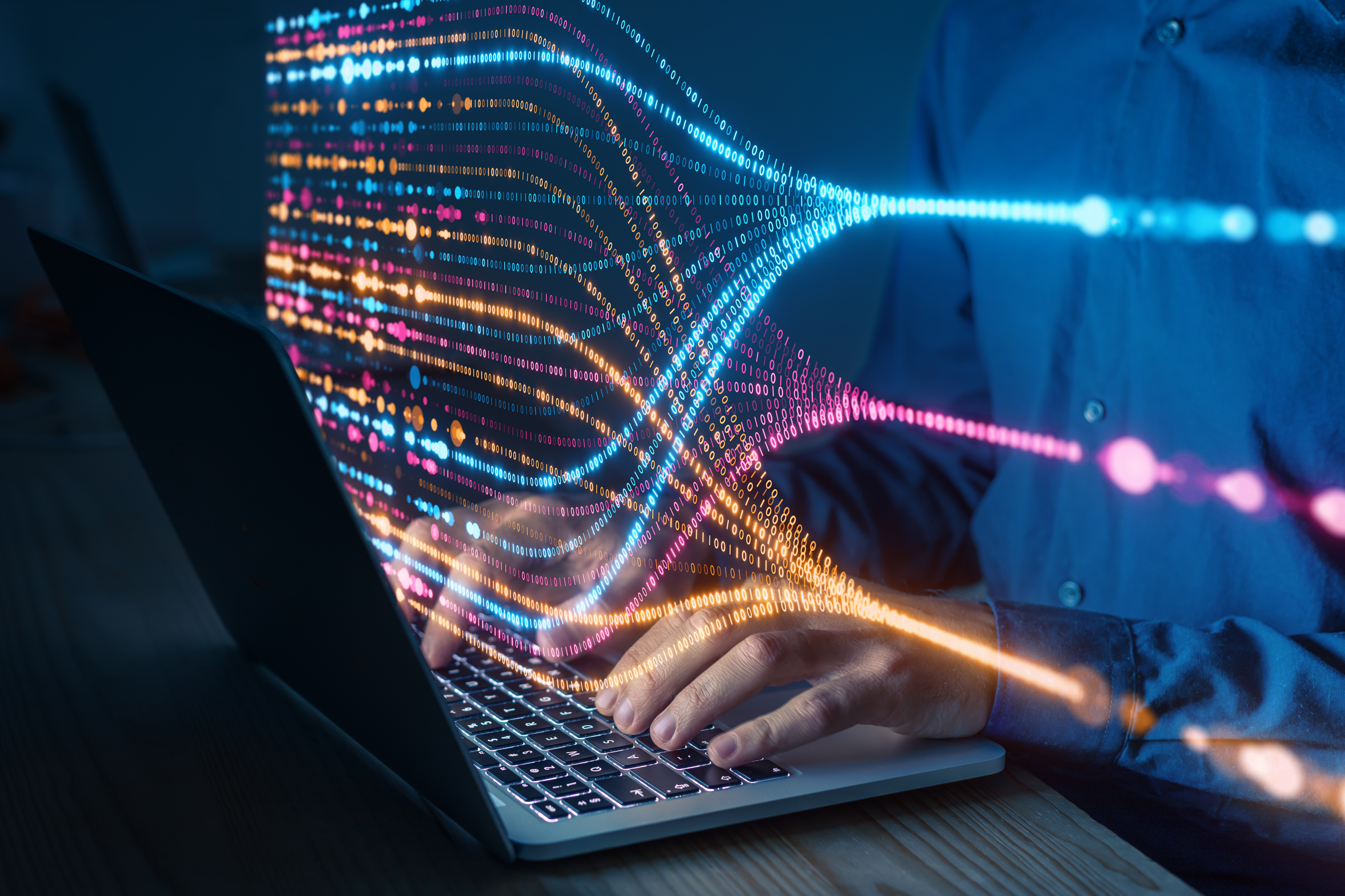 Programmer typing on laptop with colorful data flow visualization, concept of artificial intelligence, big data analysis, machine learning, and digital technology innovation